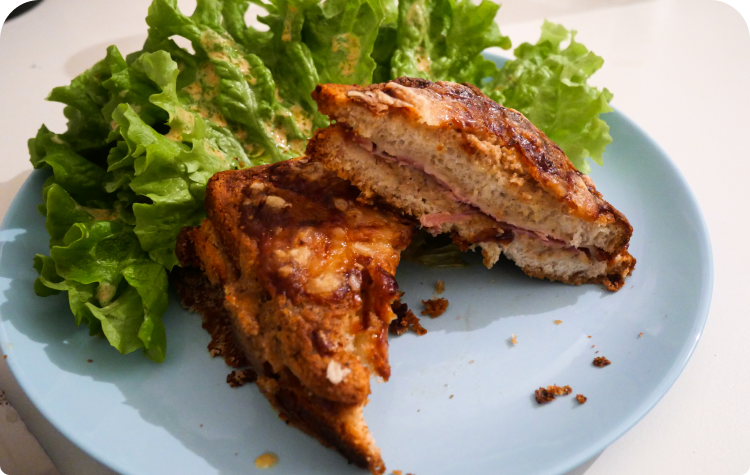 Croque monsieur avec béchamel à la farine de drêche dans une assiette accompagnée de salade verte