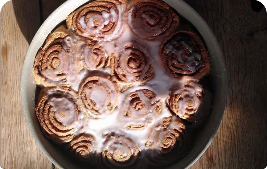 Cinnamon Rolls à la farine de drêche ambrée dans un bol, recouvert de glaçage