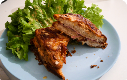 Croque monsieur avec béchamel à la farine de drêche dans une assiette accompagnée de salade verte